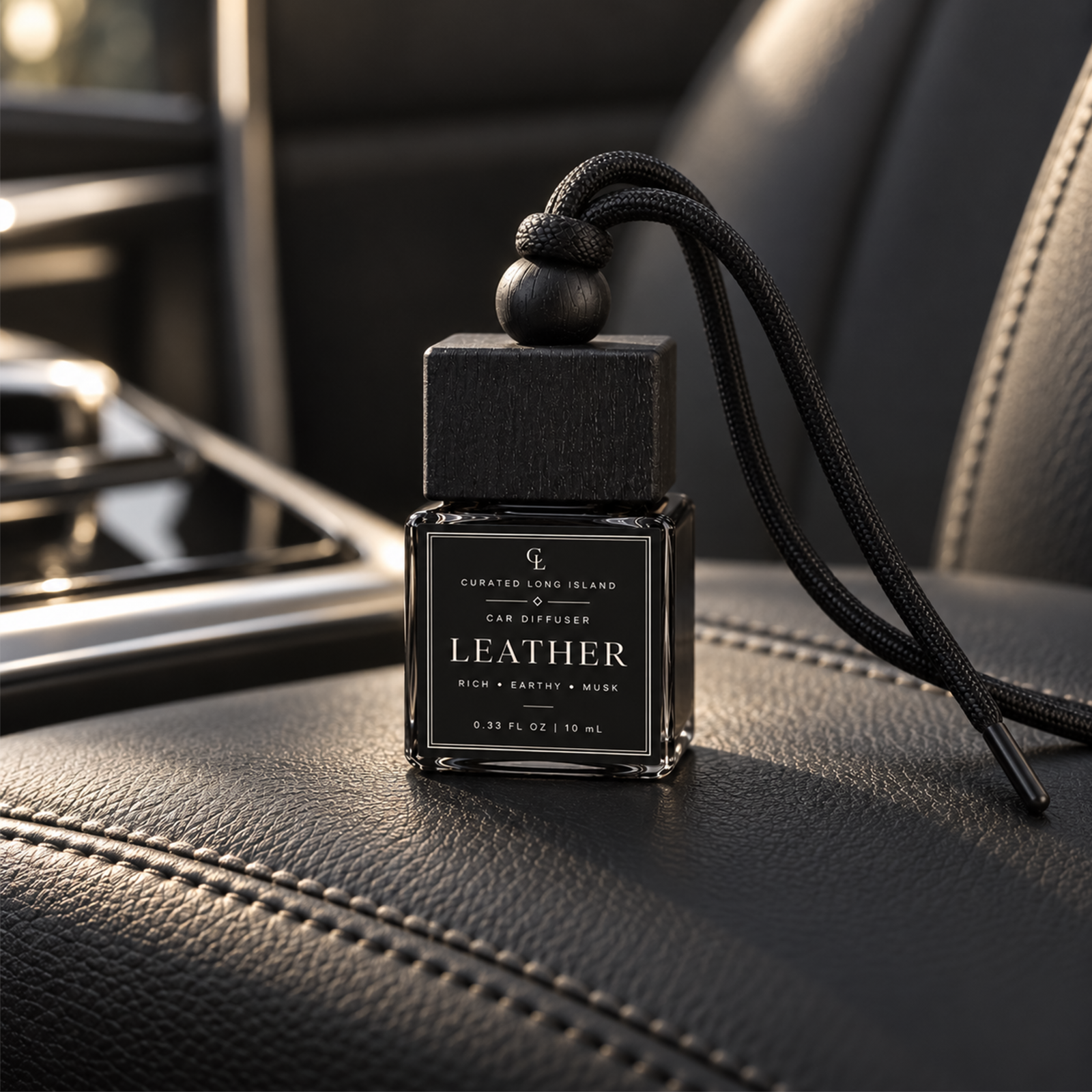 Black Leather car diffuser in a black glass bottle resting on a black leather car seat