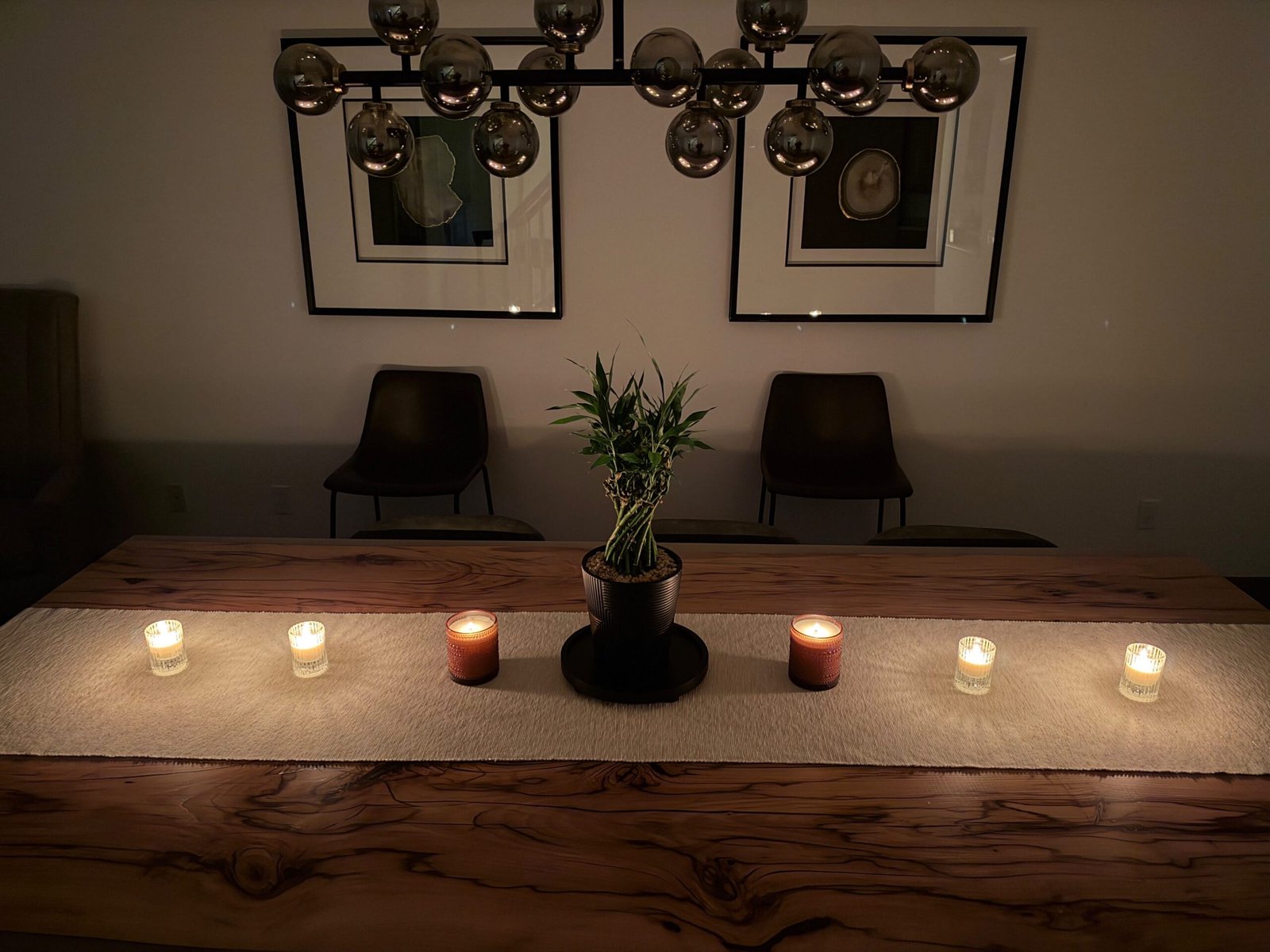 Two amber Barrel-Spiced Pumpkin candles and four small custom candles arranged along a customer's wooden dining table.