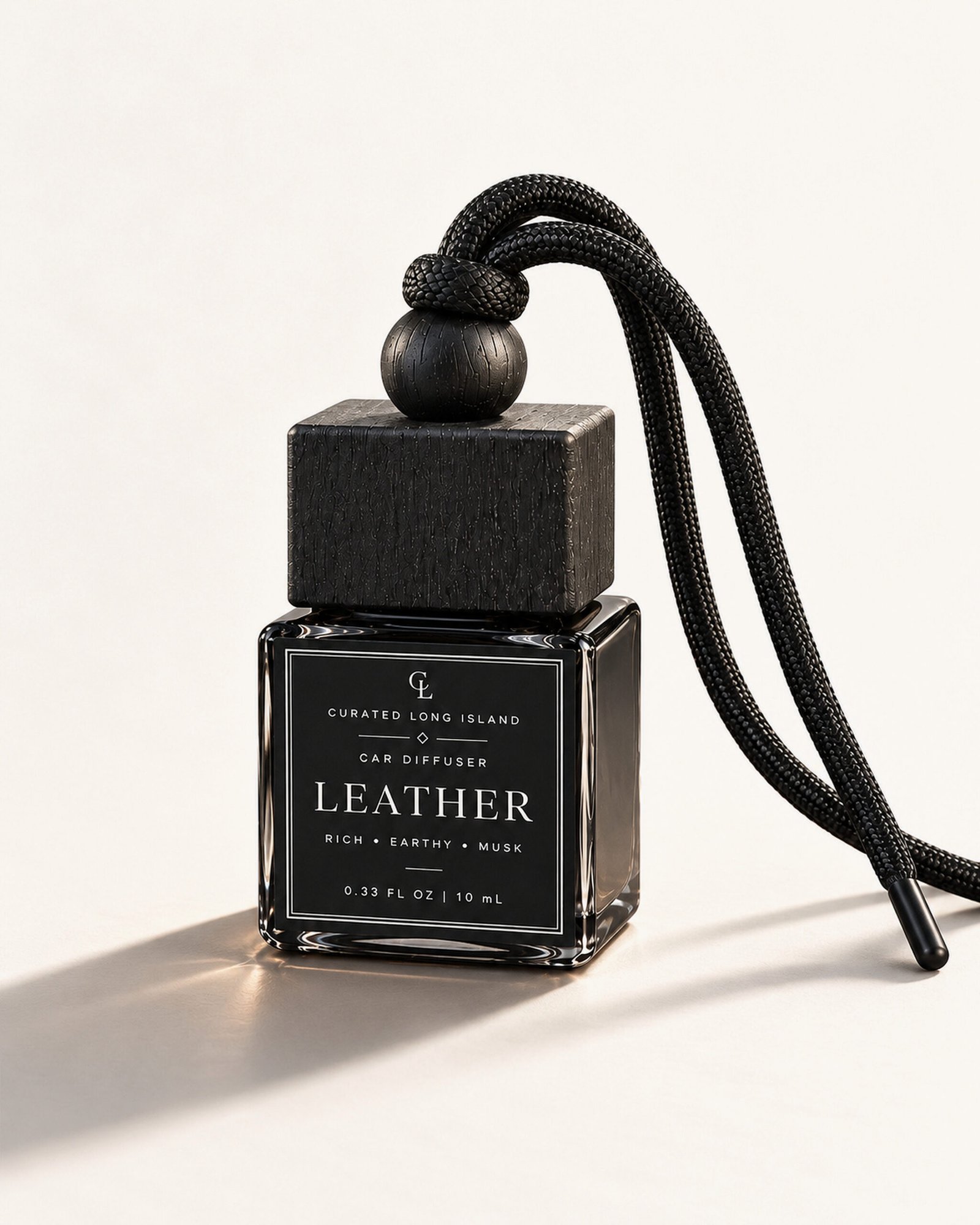 Leather hanging car diffuser in a black glass bottle with black wooden cap and black cord